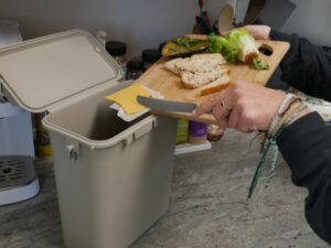 putting food into kitchen caddy for composting