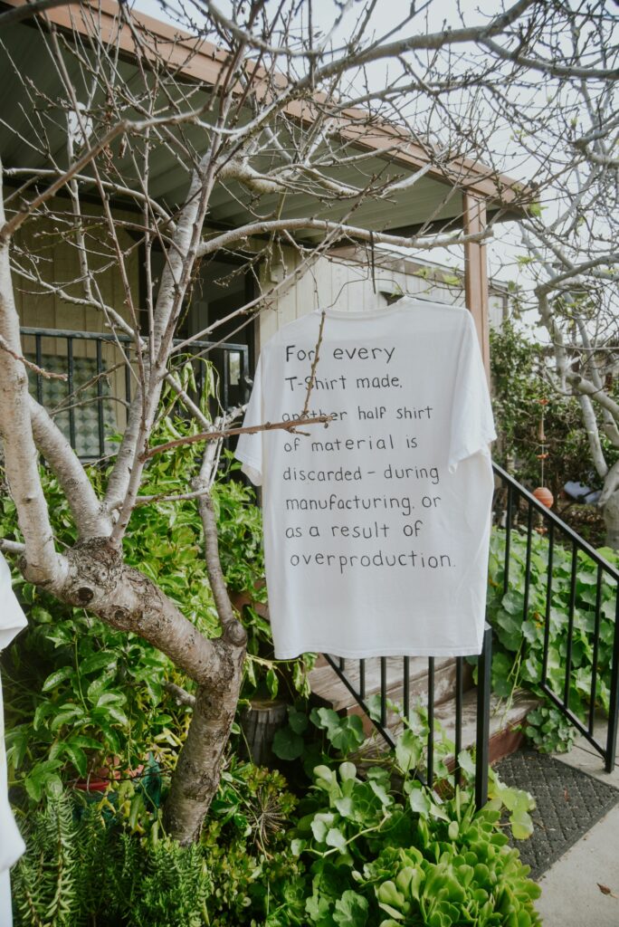 A shirt hanging from a tree with a statement on textile waste